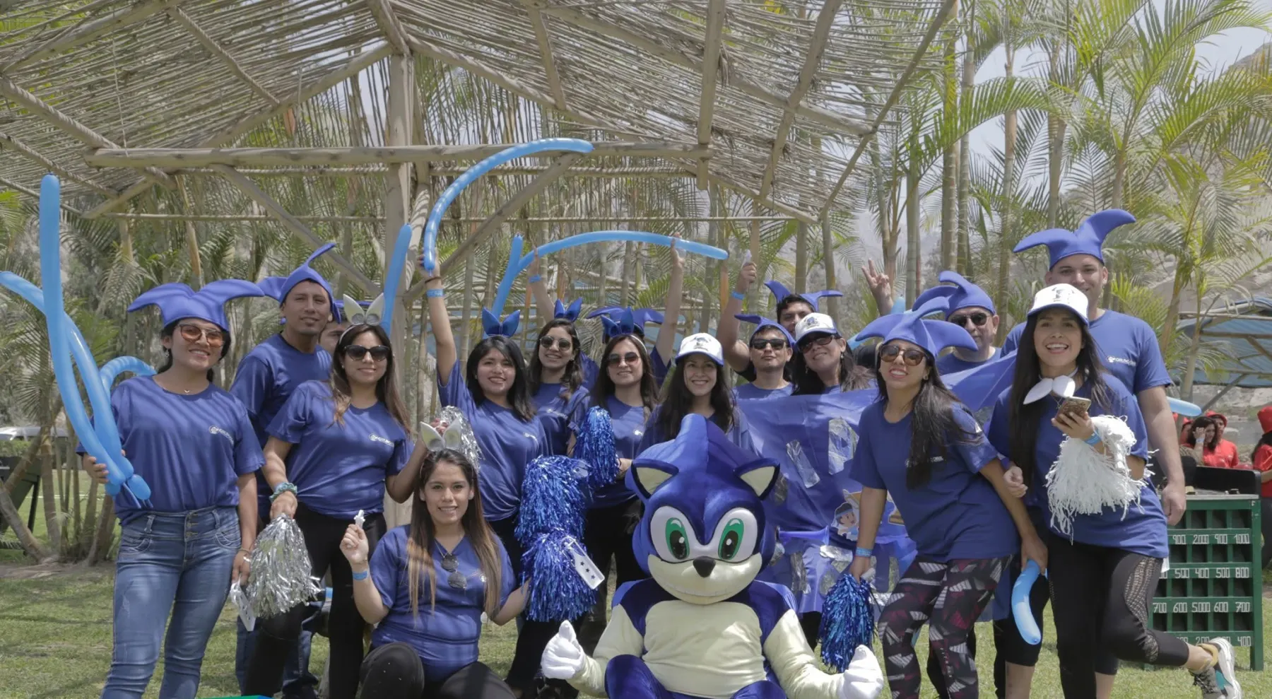 Un grupo con polos azules y pompones posa junto a la mascota del evento durante una jornada familiar